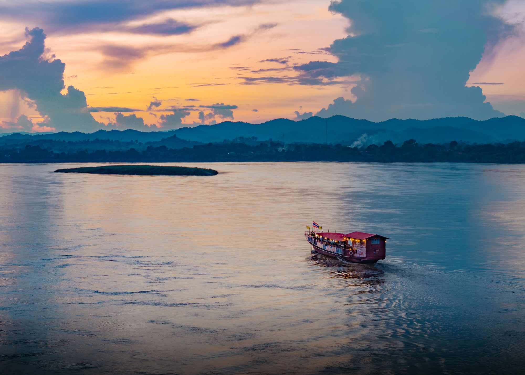 Barco tradicional navegando el río Mekong al atardecer